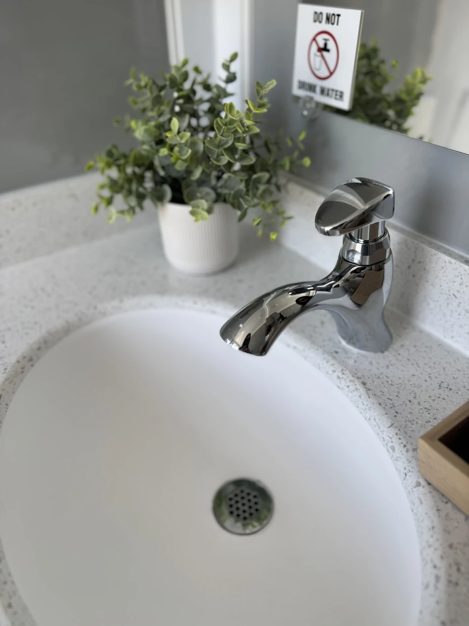 Close-up of the running-water sink and chrome faucet inside the restroom trailer